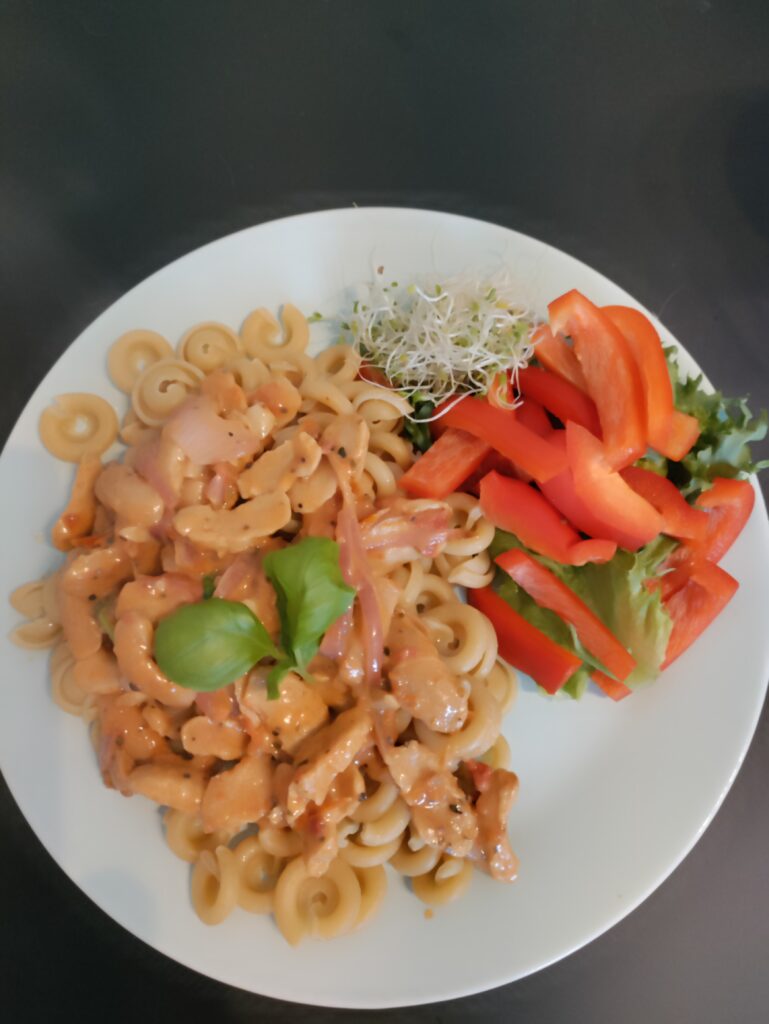 Soijasuikaleita sipulissa ja tomaattikastikkeessa sekä pastaa ja kasviksia lautasella